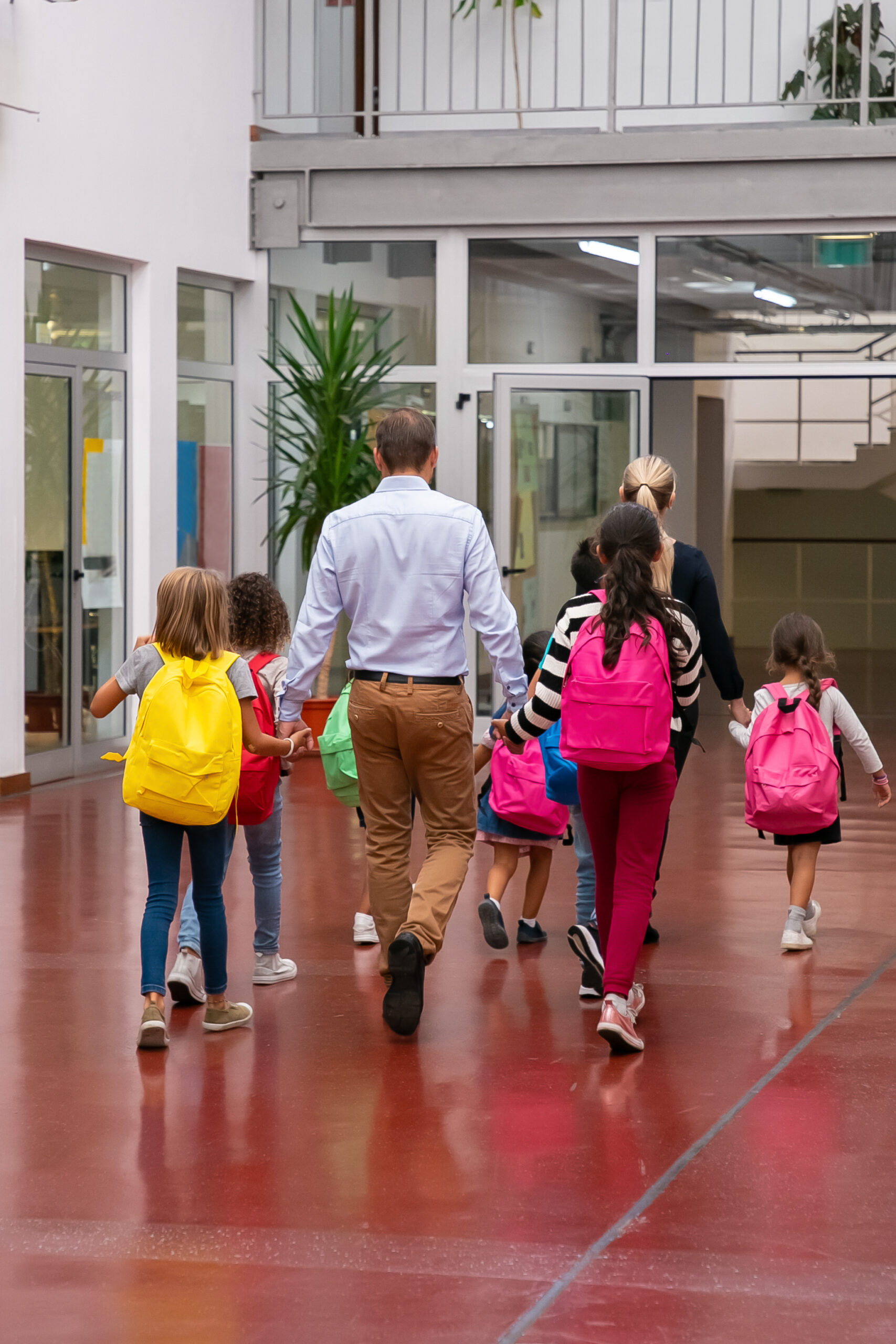 Schoolkids with bright backpacks walking through hallway